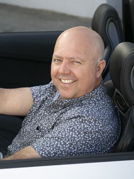 Chris Hicks, Financial Services Manager at CredRev, smiling behind the wheel of a car